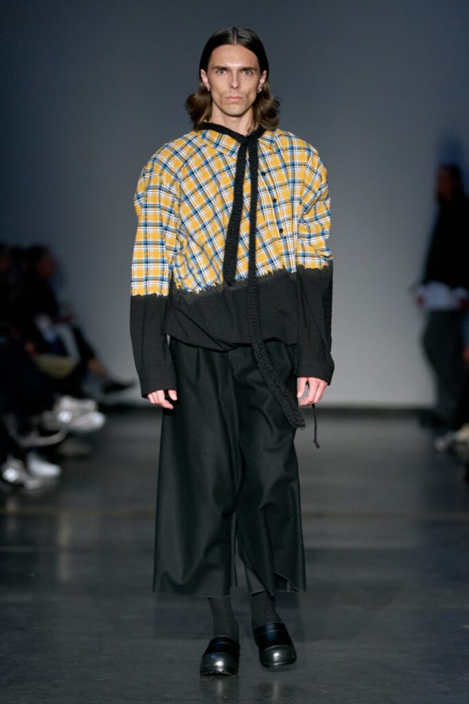 A relaxed long-sleeve top in black and yellow check pattern paired with black pants.