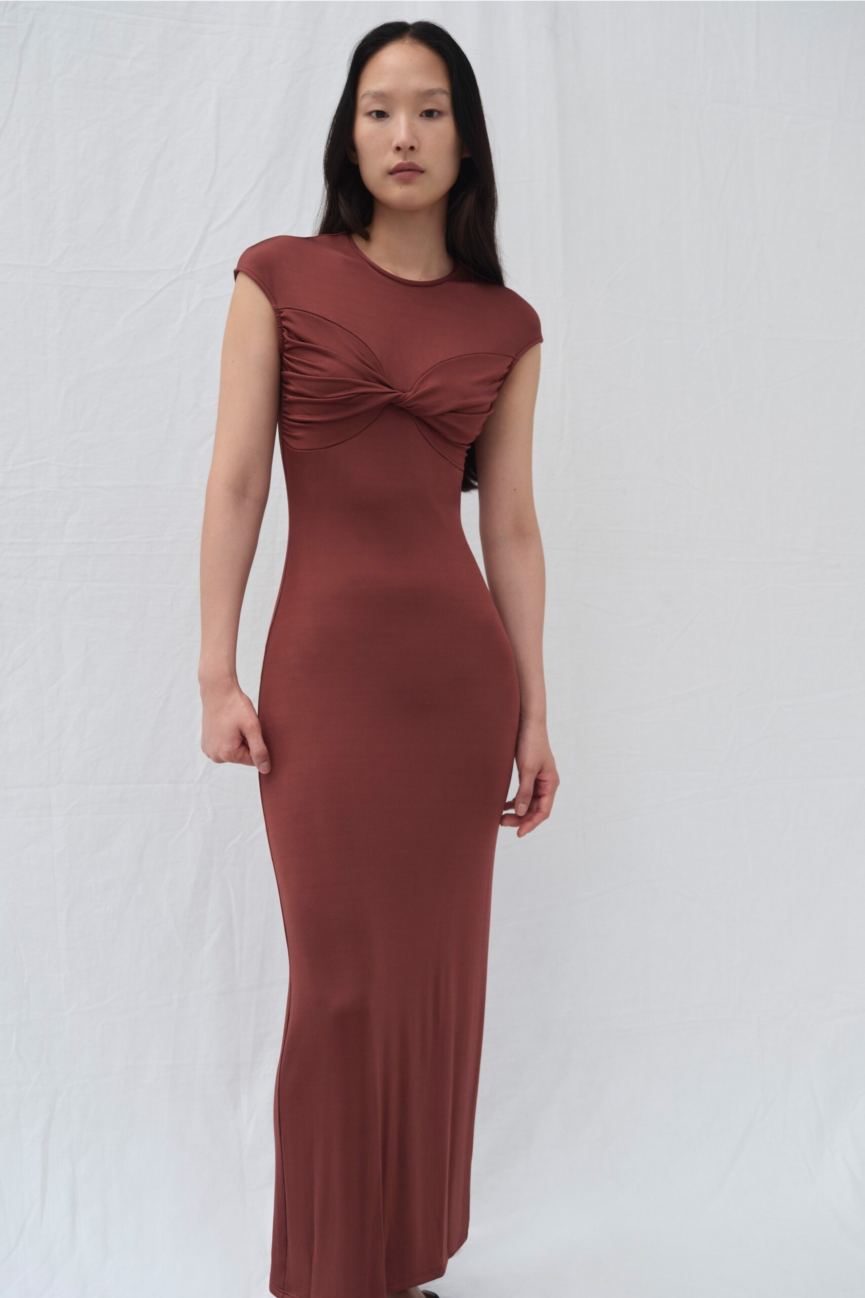 A fitted brown dress with short sleeves and a V-neckline featuring ruched detailing.
