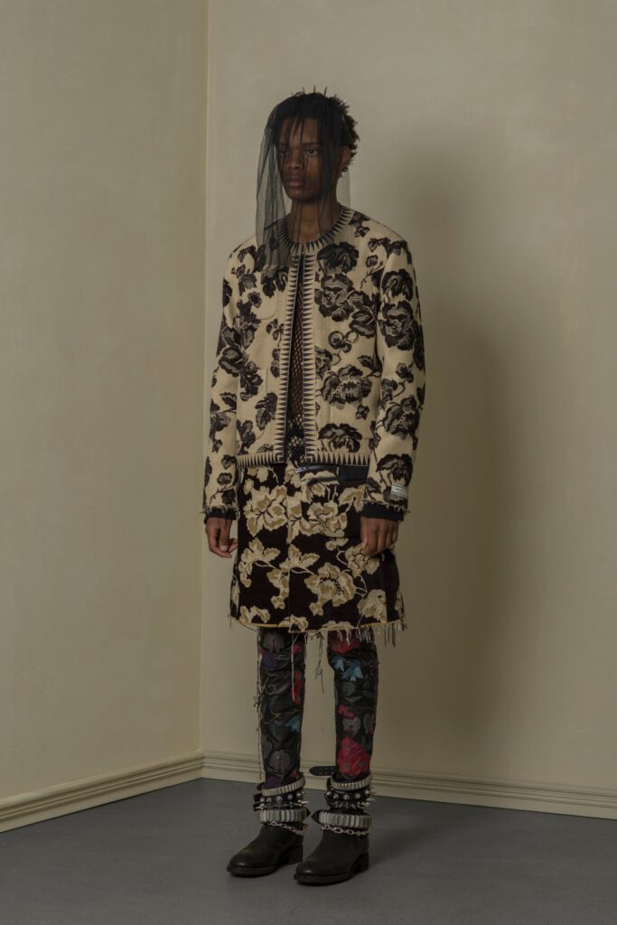 A fitted beige jacket with floral embroidery paired with a black embroidered skirt.