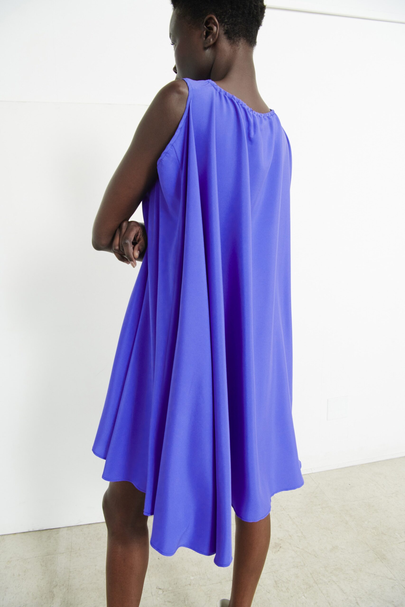 A relaxed blue silk sleeveless dress with a high neckline and asymmetric design.