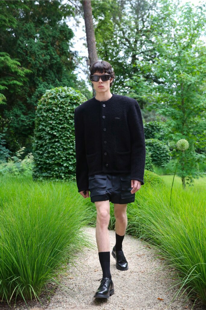 An oversized black jacket with long sleeves and a collared design paired with black shorts.