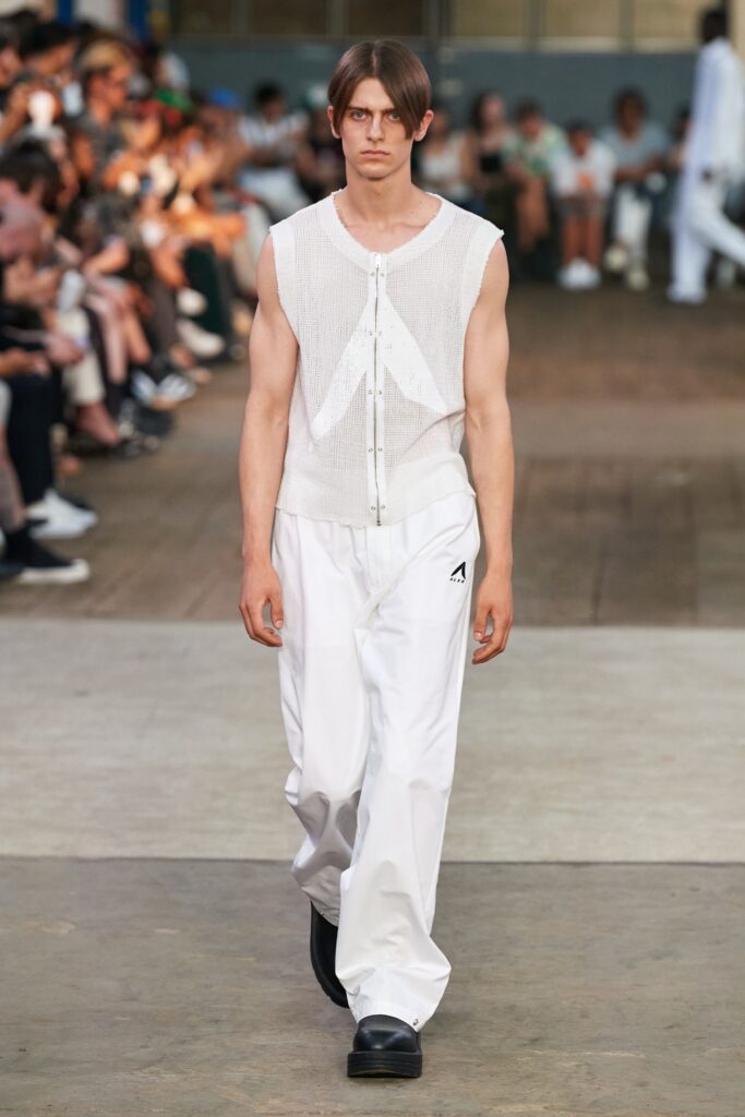 A relaxed white sleeveless top with a collared design paired with loose-fitting pants.