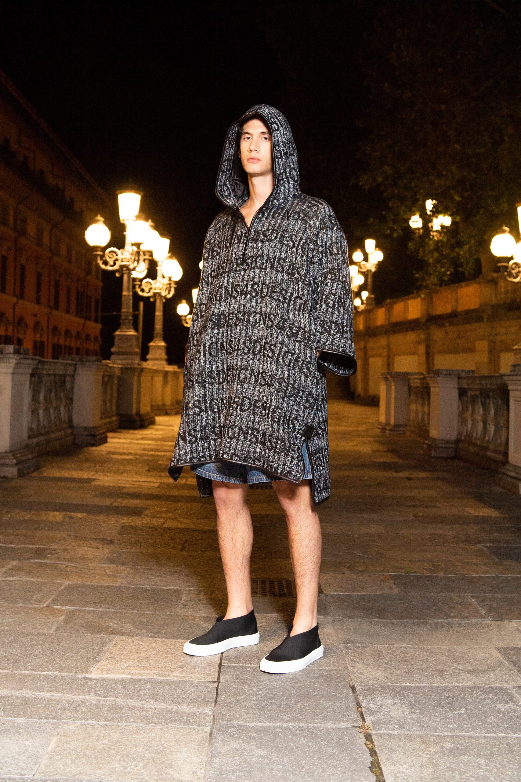 A relaxed black cotton coat with long sleeves and a hood, featuring a printed design.