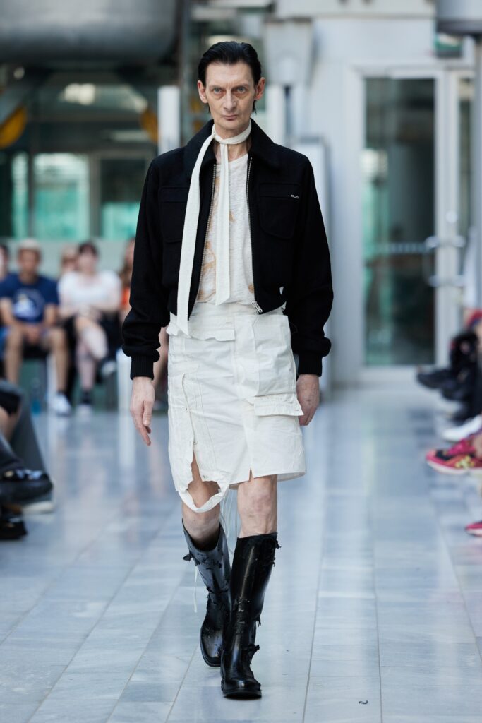 An oversized black jacket paired with an asymmetric white skirt, creating a striking runway look.