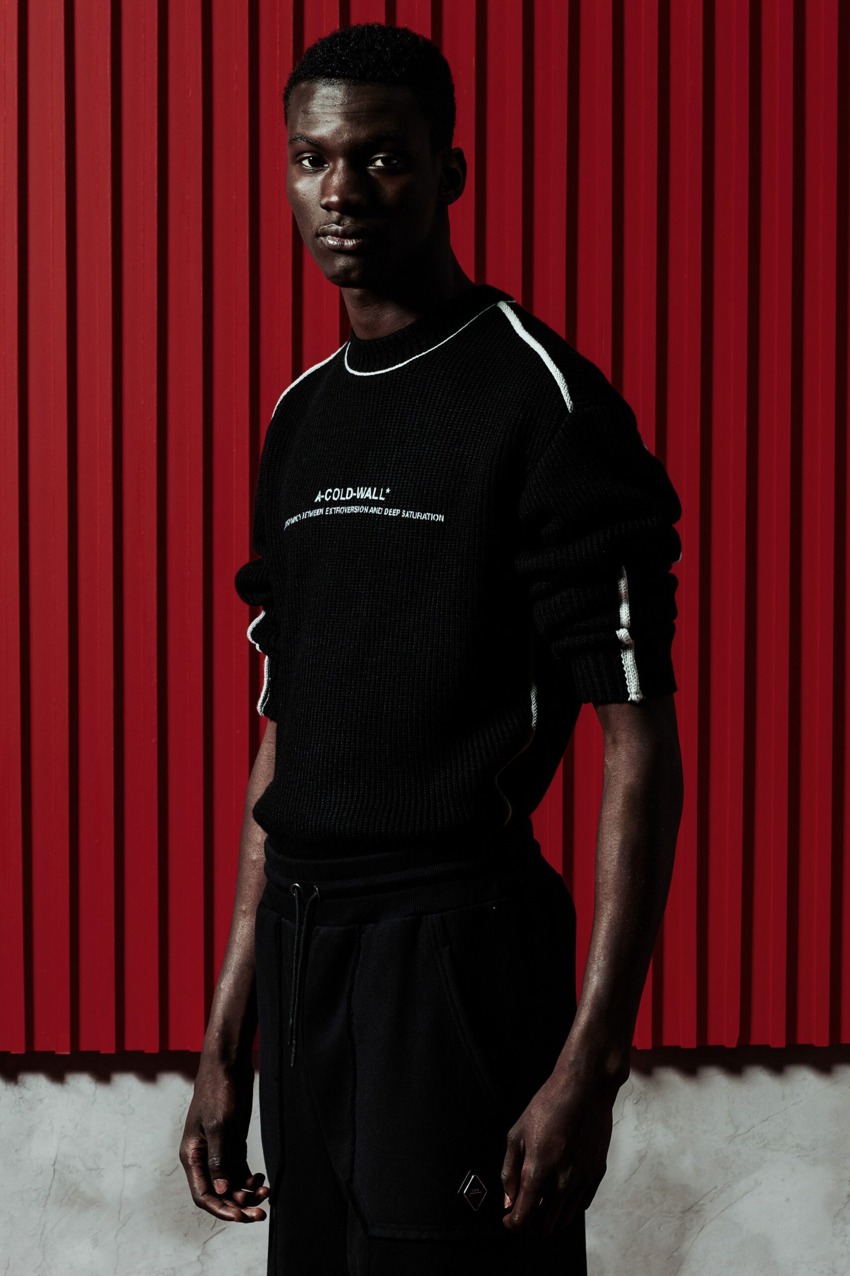 A fitted black cotton sweater with long sleeves paired with matching black pants featuring a printed detail.