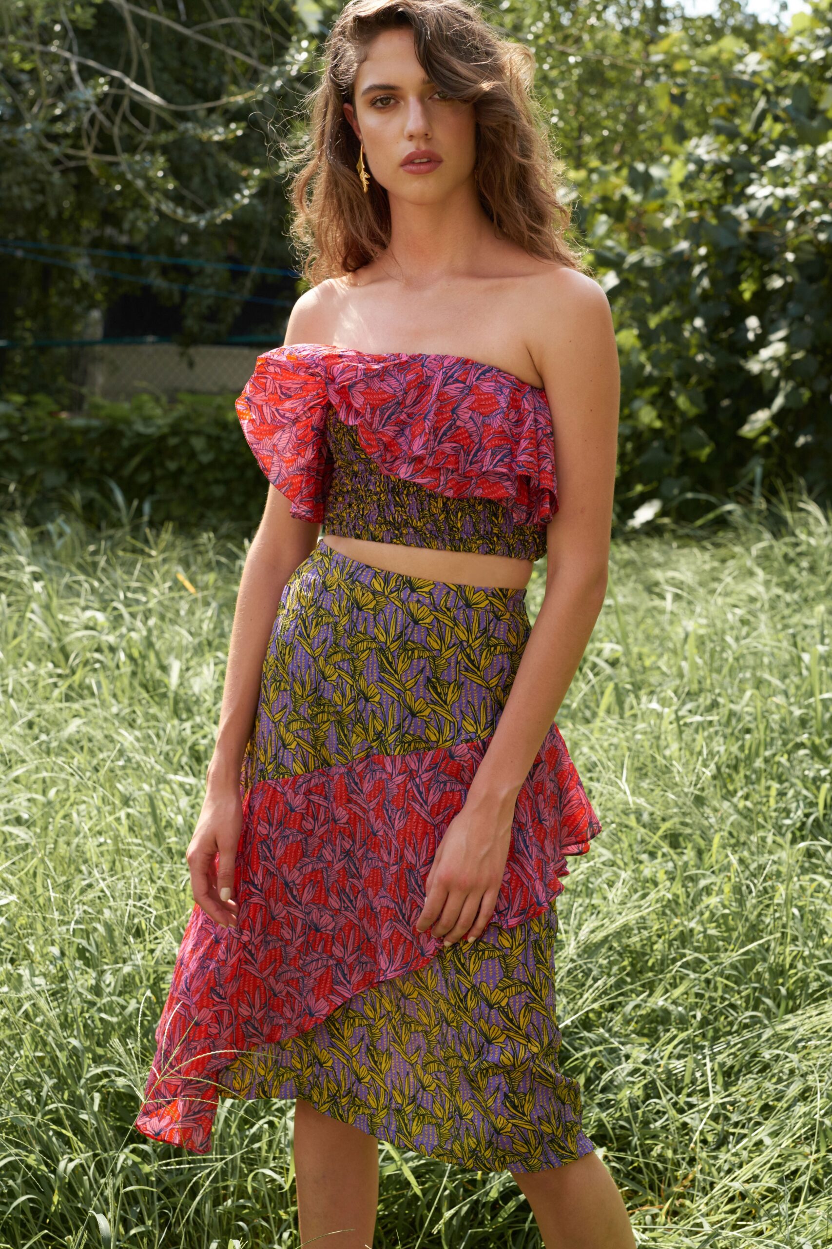 A fitted red and purple cotton dress with an off-shoulder design and tiered asymmetric silhouette.