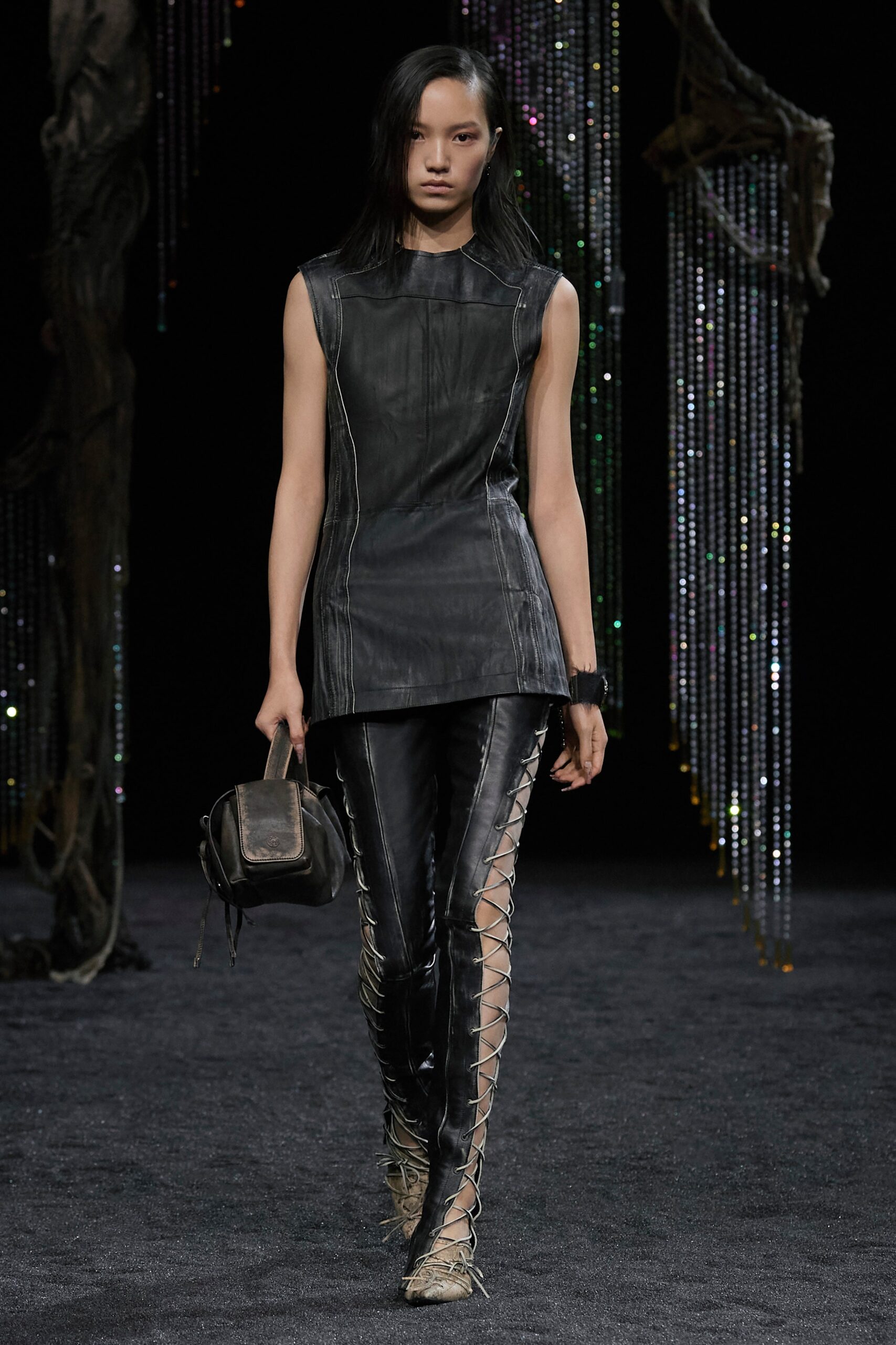A fitted black leather sleeveless top with high-neck and asymmetric design paired with matching pants.