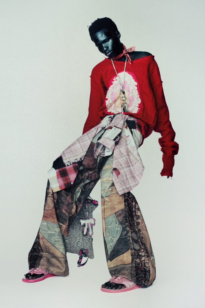 A relaxed red long-sleeve top with asymmetric layered multicolor pants.