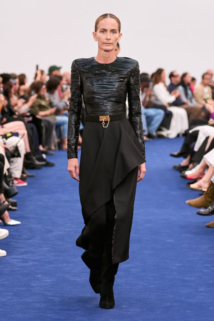 A fitted black silk dress with long sleeves and an asymmetric, draped design.