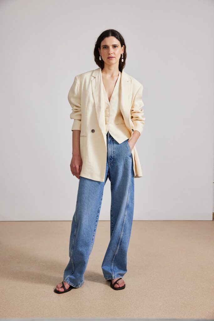 A relaxed beige blazer paired with wide-leg blue denim pants and a V-neck top.