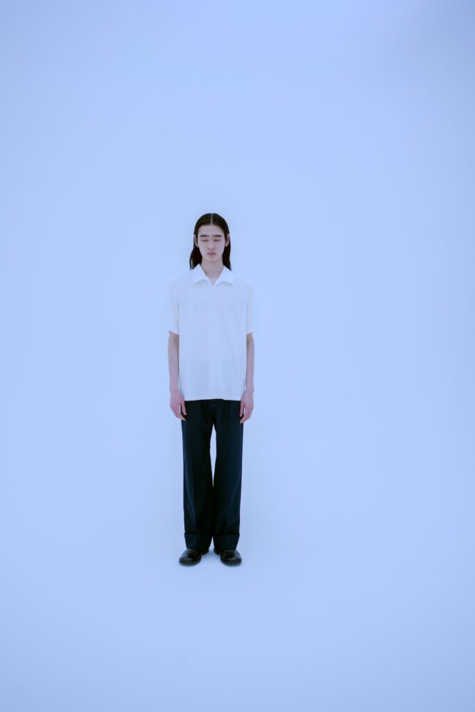 A relaxed white short-sleeve collared shirt paired with straight-leg black pants.