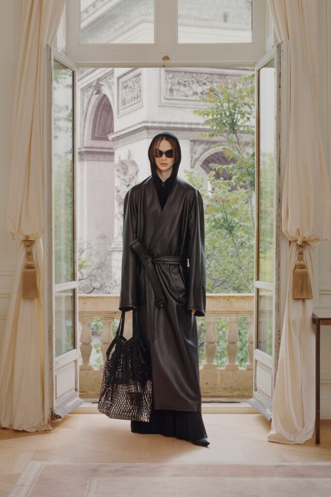A fitted black leather coat dress with long sleeves and a belted design.