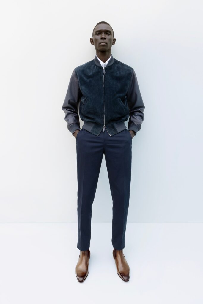 A fitted black leather jacket with long sleeves paired with structured navy pants.