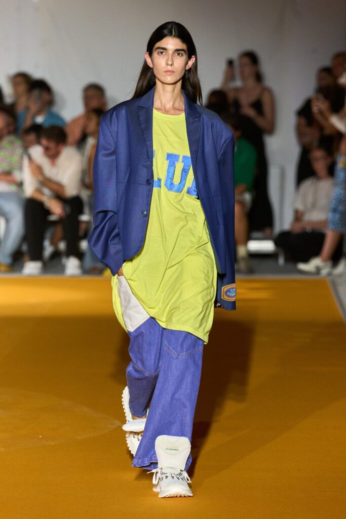 A relaxed blue jacket paired with a short-sleeve green t-shirt featuring a printed design.