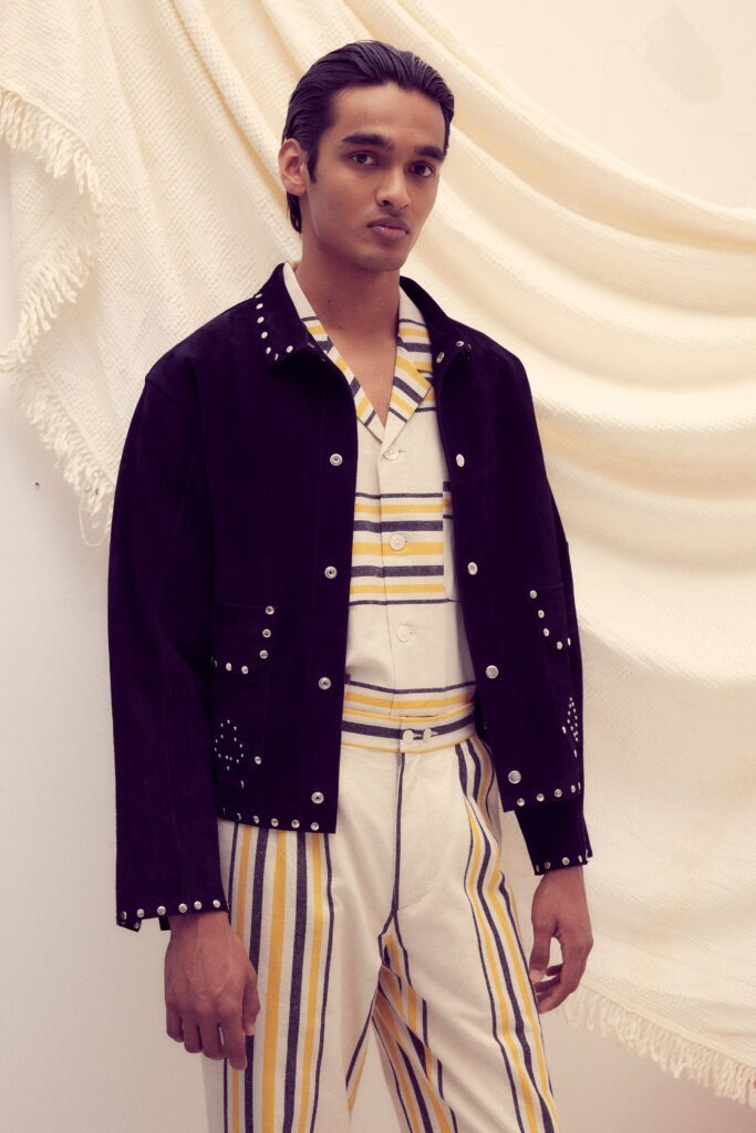 A fitted black jacket with long sleeves paired with white striped pants.