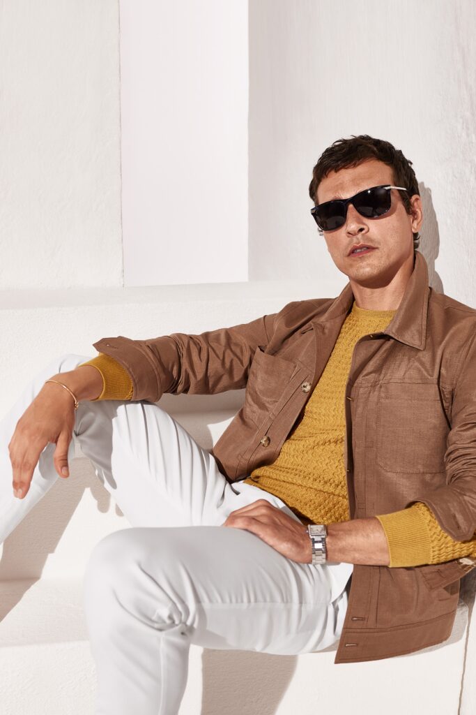 A fitted brown jacket over a yellow long-sleeve sweater, paired with white pants.