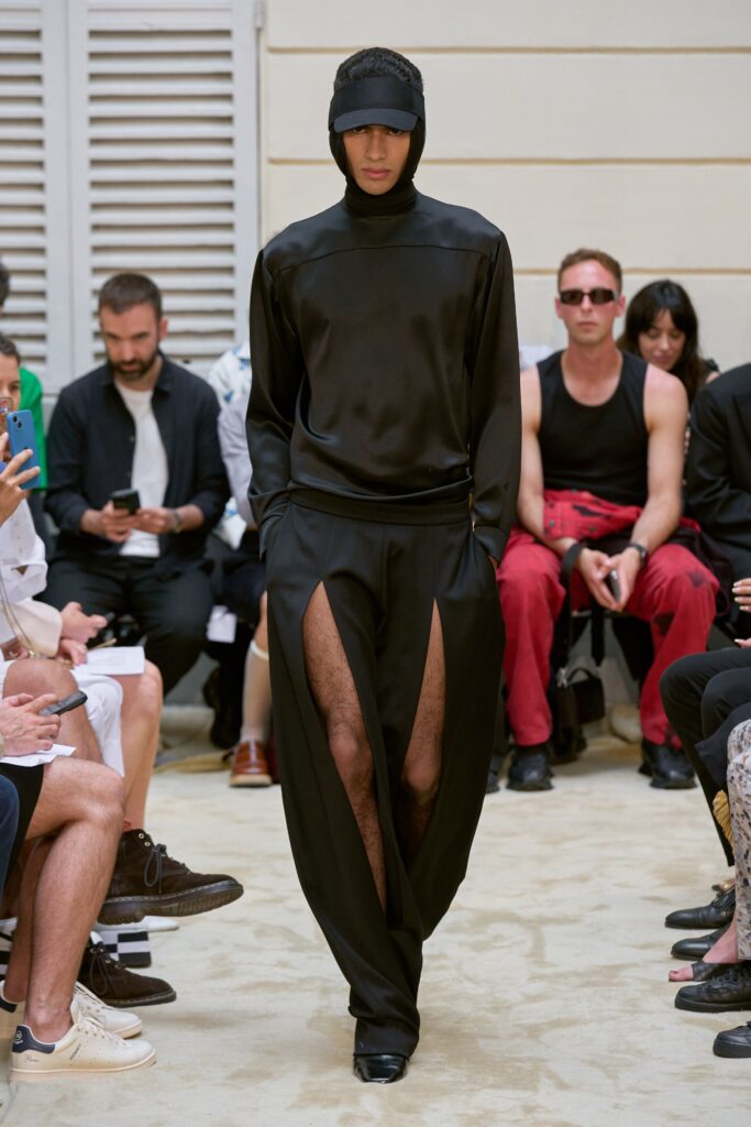 A relaxed black silk long-sleeve top with high-neck and asymmetric cutout pants.