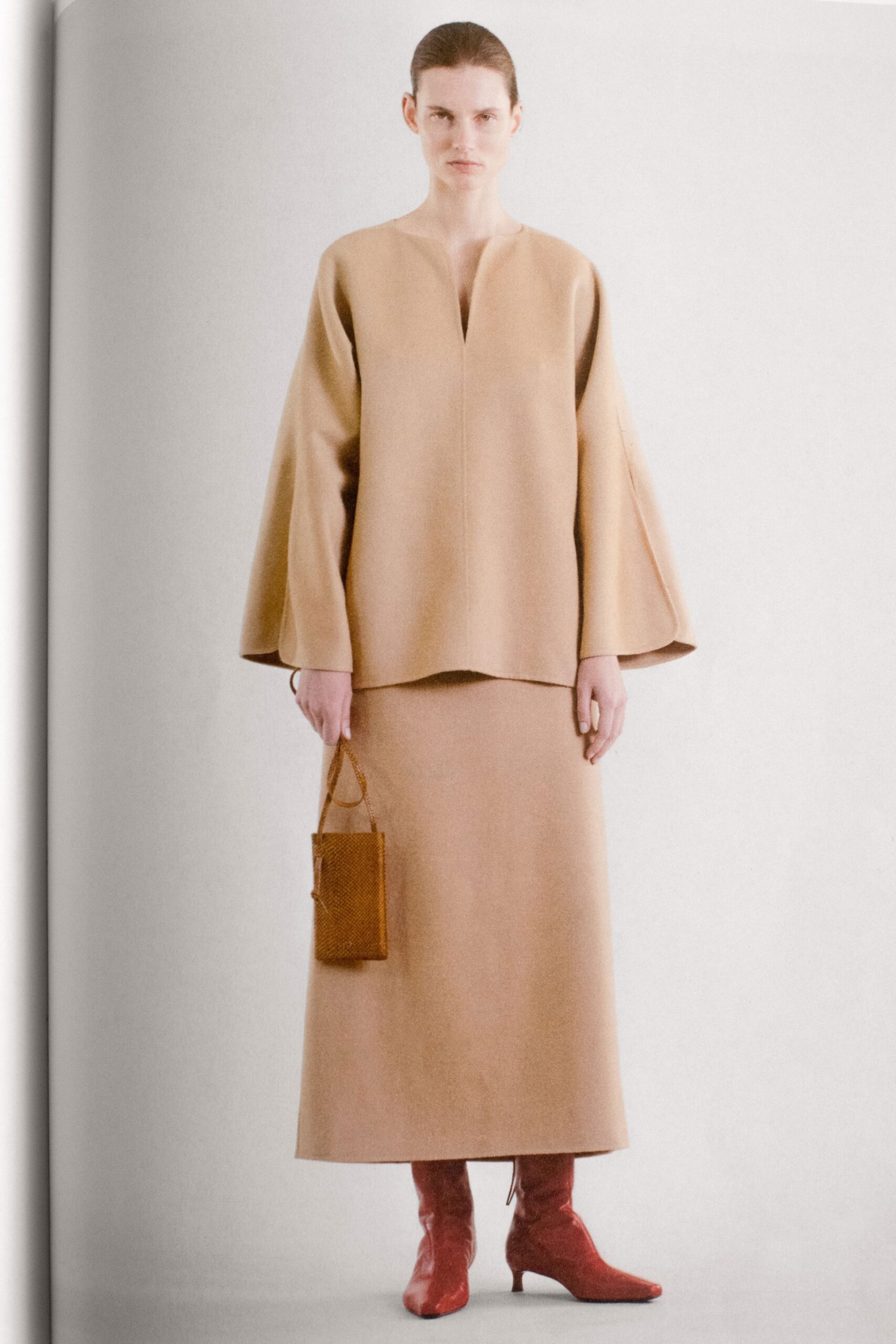 A relaxed beige wool top with long sleeves and a V-neck, paired with a matching skirt.
