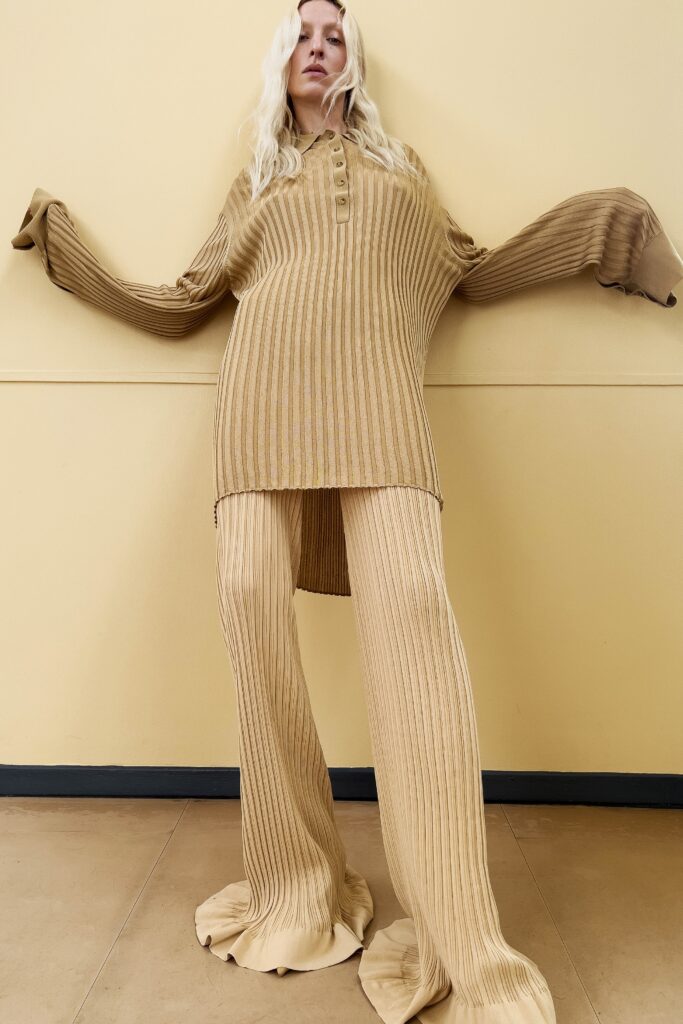 An oversized beige knit top with long sleeves and a collared neckline paired with matching ribbed pants.