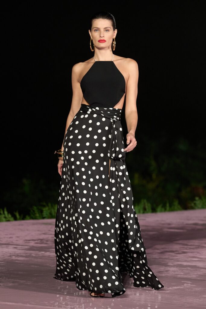 A fitted sleeveless black and white polka-dot dress with a halter neckline and tiered design.
