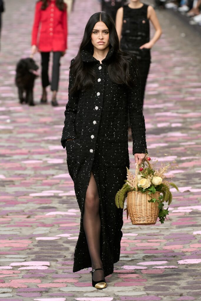 A fitted black cotton dress with long sleeves, a collared neckline, and a buttoned front with a slit.
