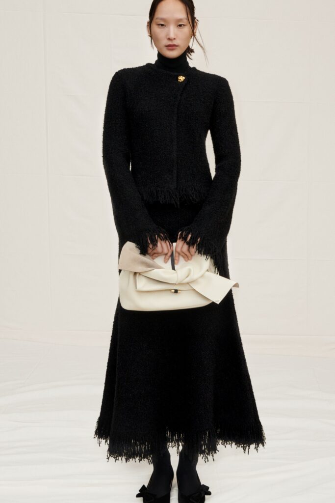 A fitted black wool long-sleeve dress with a high neckline and fringed A-line silhouette.