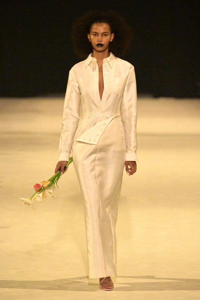 A fitted white silk dress with a V-neckline and asymmetric design details.
