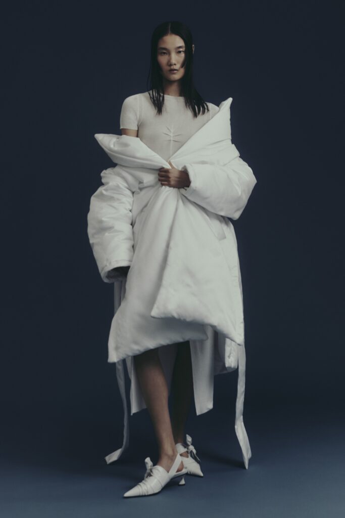 A relaxed white dress with a layered design and long sleeves, complemented by a collared coat.
