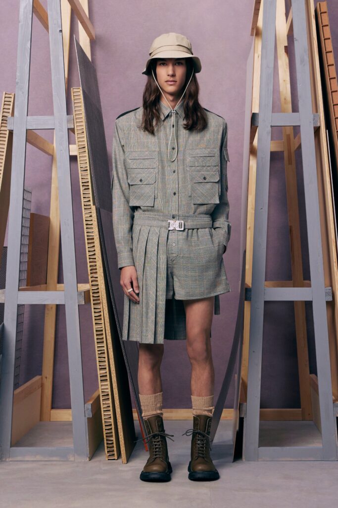 A gray cotton shirt-dress with pleated detailing and matching shorts, styled with a bucket hat.