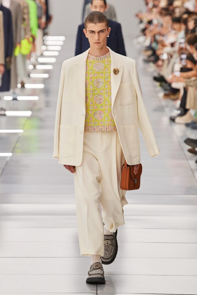 A relaxed white suit paired with a long-sleeve pink sweater featuring a buttoned design.