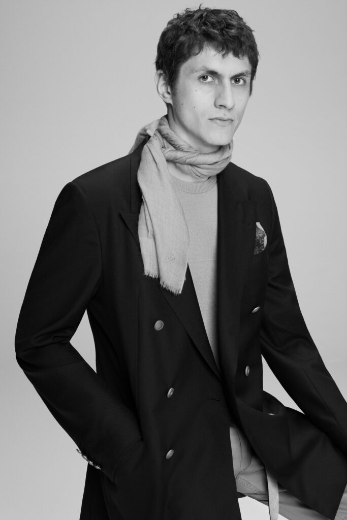 A fitted black blazer paired with a gray turtleneck, featuring a collared design and buttoned detail.