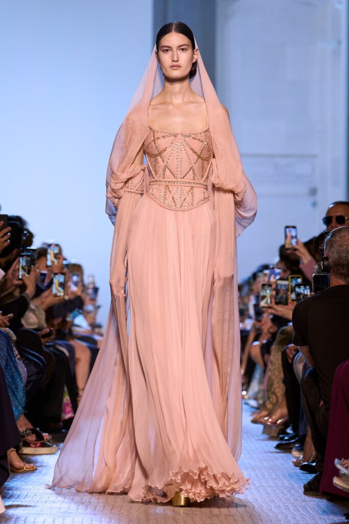 A fitted pink silk gown with a V-neckline and layered design details.