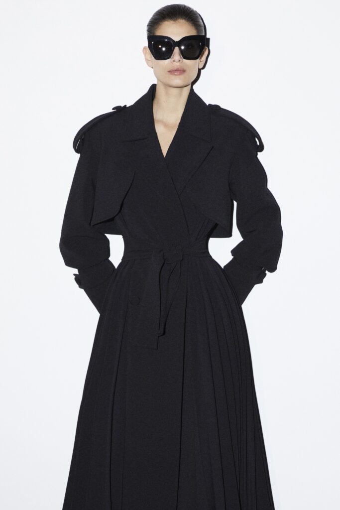 A fitted black wool dress with long sleeves, a collared neckline, and pleated detailing.