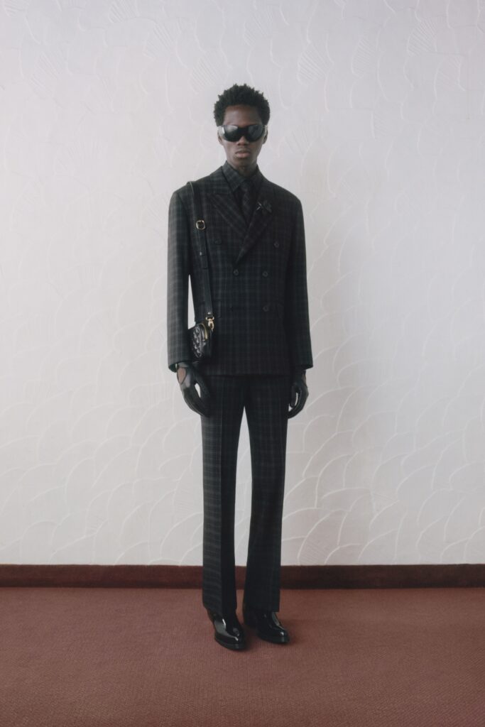 A tailored black wool suit with long sleeves and a collared design featuring a checked pattern.