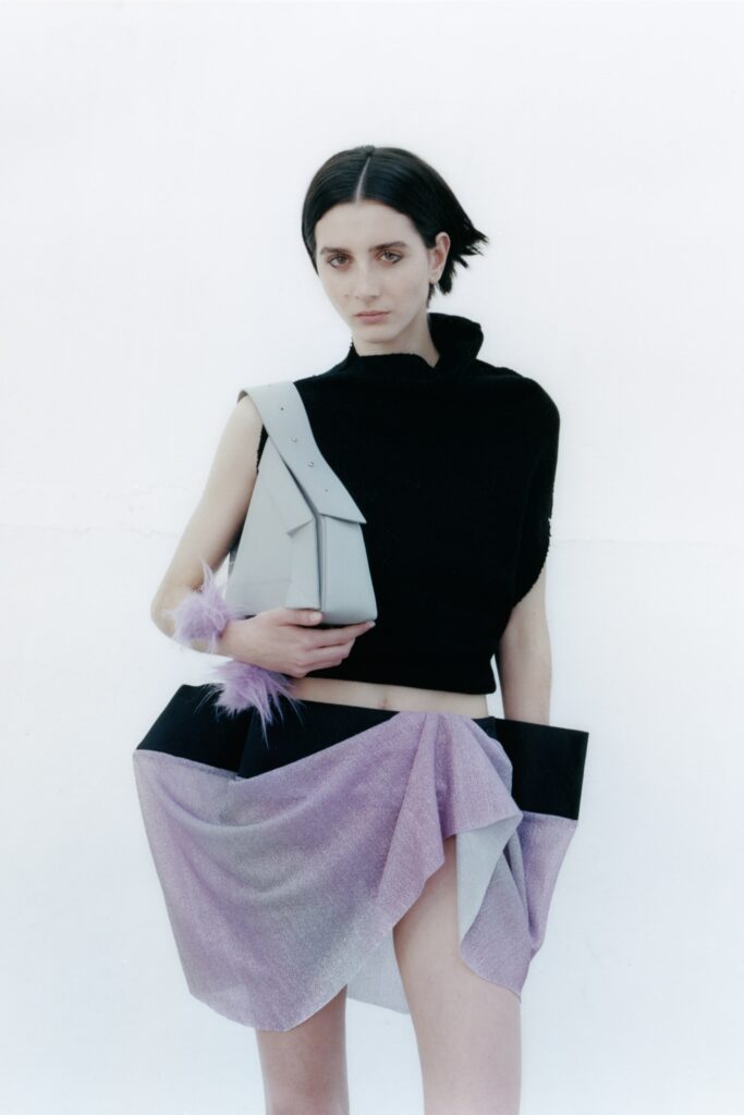 A fitted black sleeveless top paired with an asymmetric layered purple skirt.
