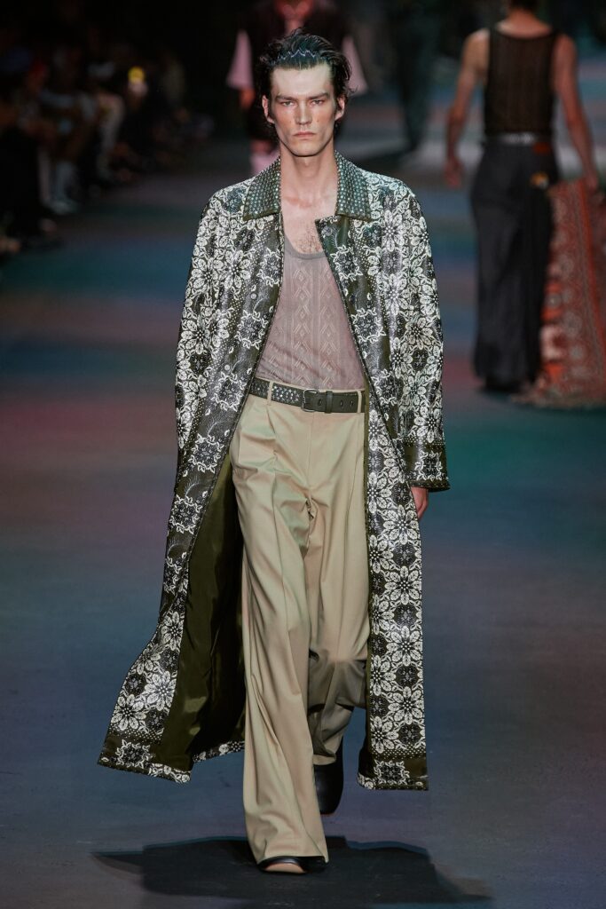 A relaxed-fit printed black coat paired with wide-leg beige pants.