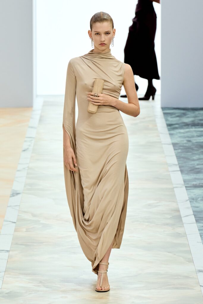 A fitted beige silk dress with a high neckline and draped design detail.