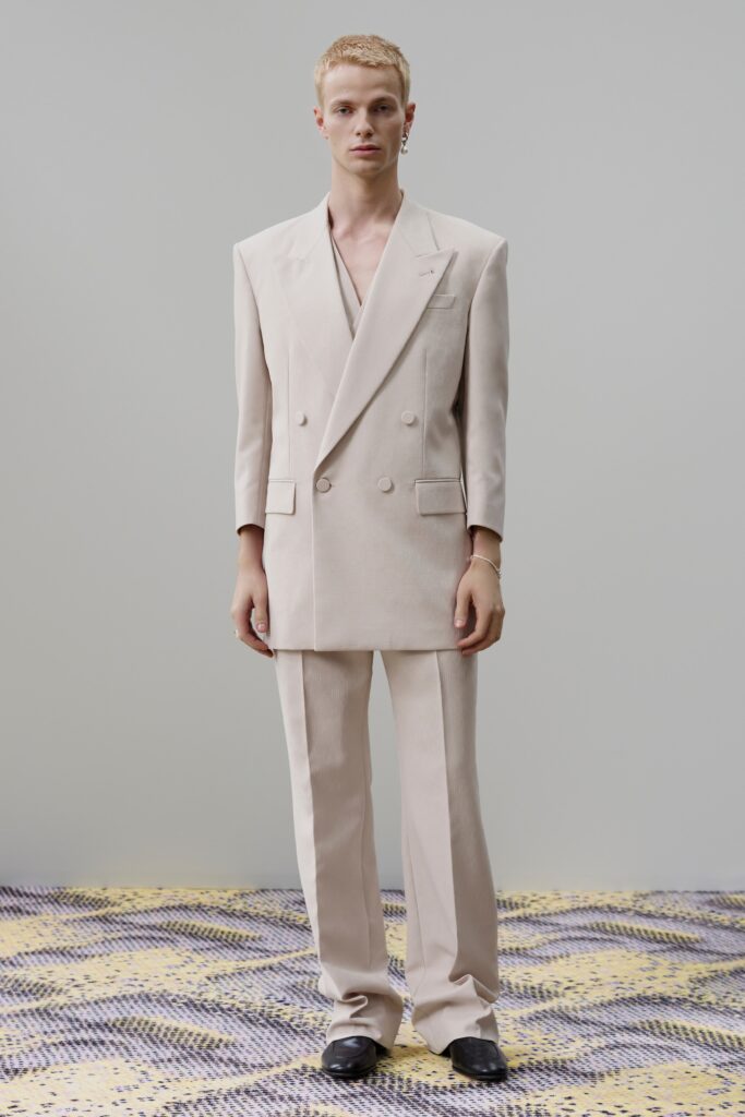 A tailored beige double-breasted suit with long sleeves and a collared design.