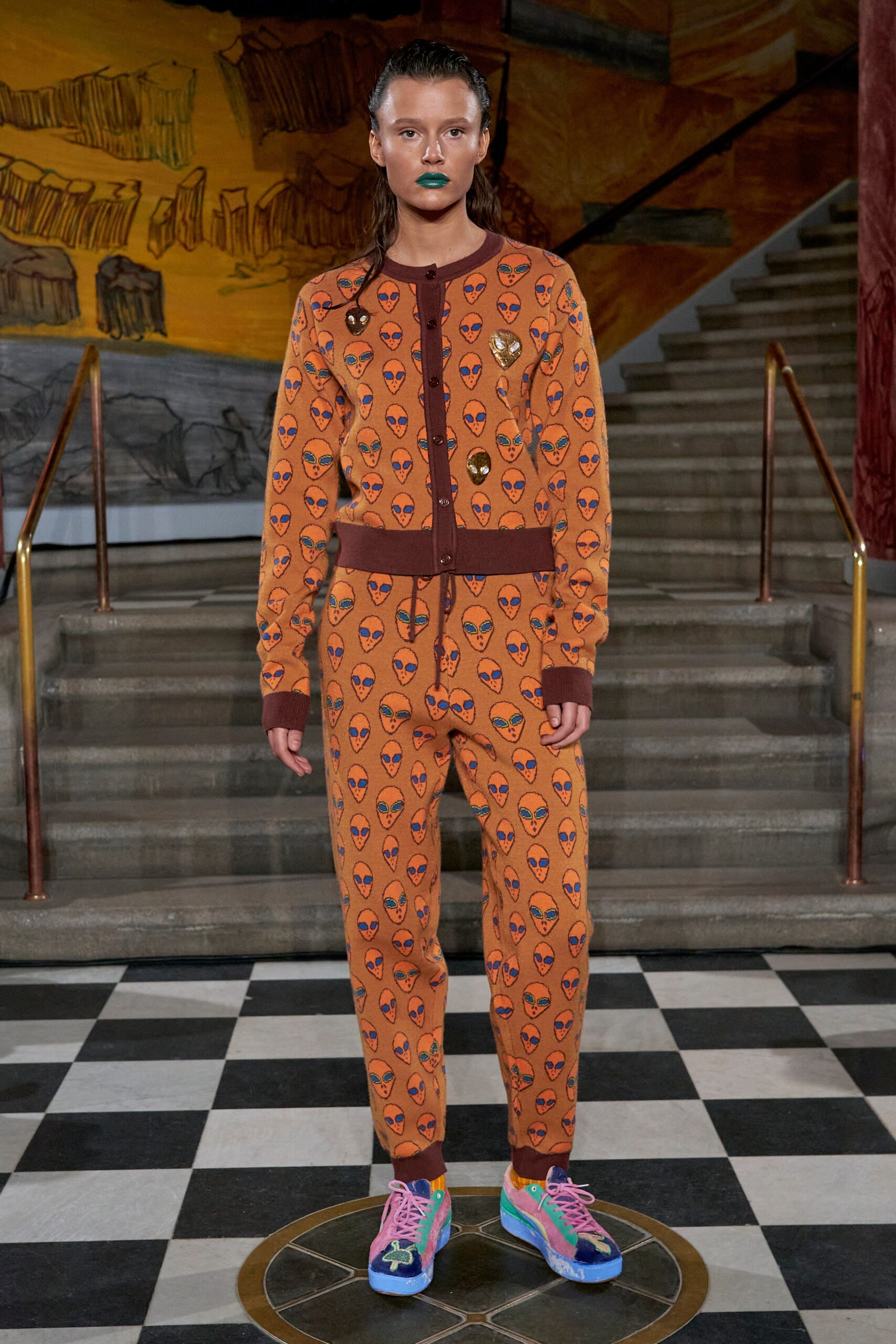 A relaxed orange jumpsuit with long sleeves, a collared neckline, and a playful printed design.