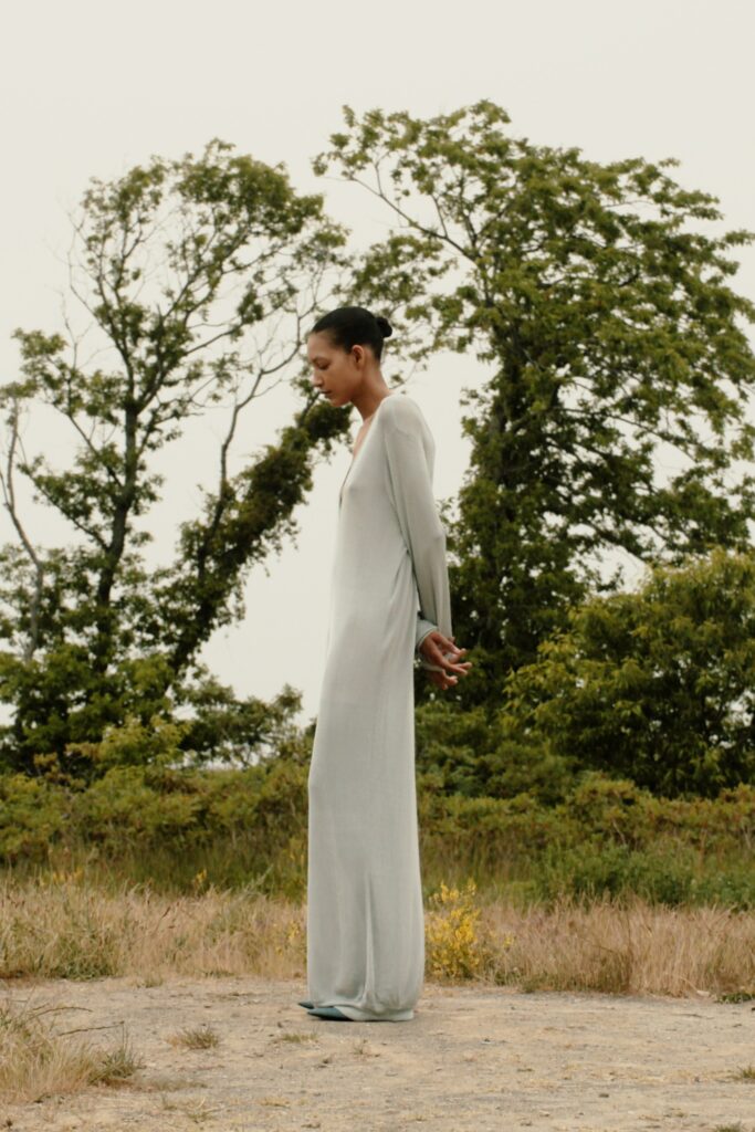 A relaxed gray silk long-sleeve dress with a V-neckline and straight-leg silhouette.