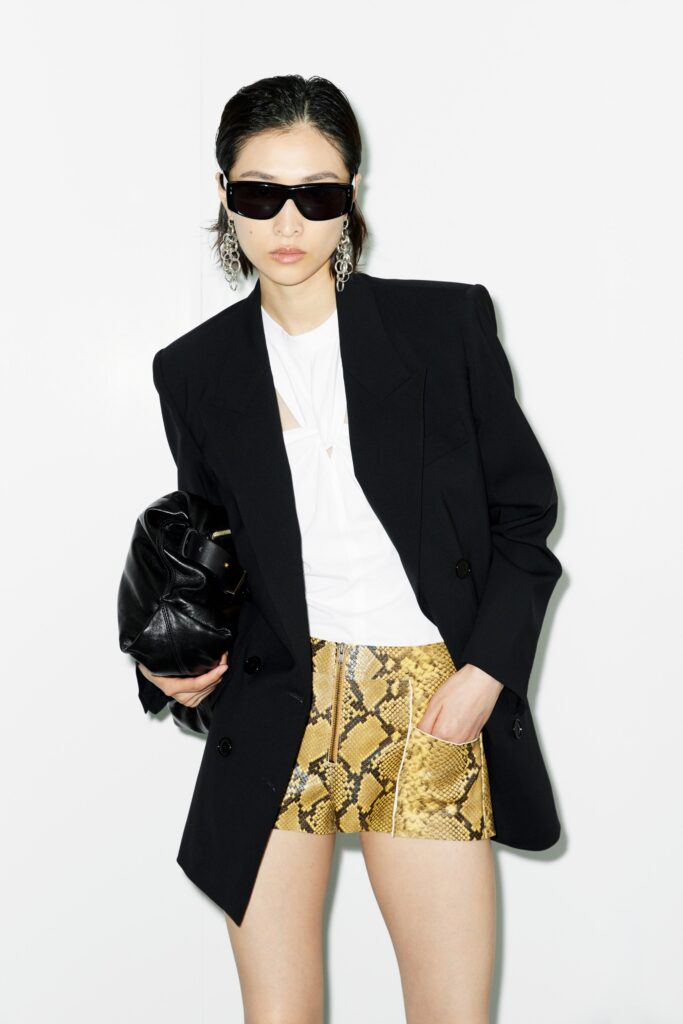A fitted black jacket paired with stylish snake-print shorts, featuring an asymmetric design.