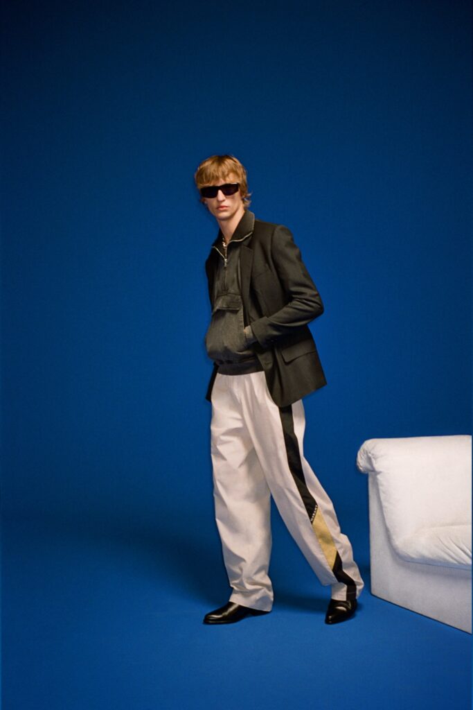 A relaxed black jacket with a collared neckline paired with white striped pants.