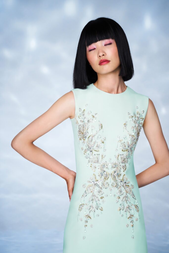 A fitted mint silk sleeveless dress with intricate embroidery detailing.