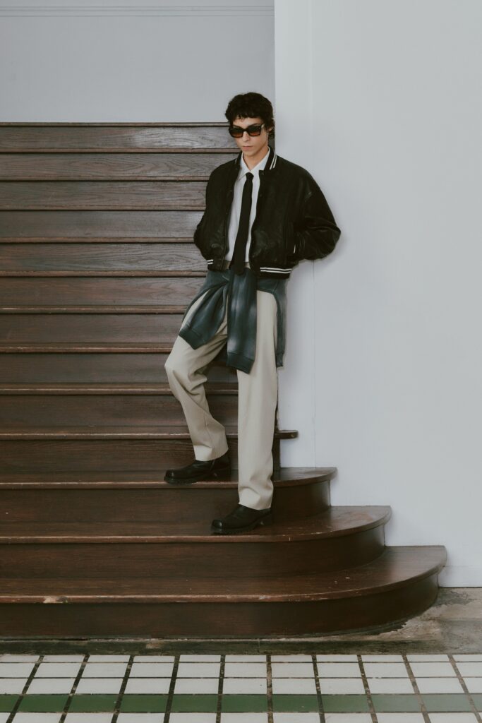 A relaxed black jacket with a collared neckline paired with straight-leg beige pants.