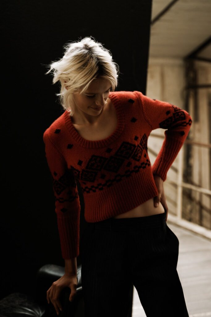 A fitted red wool sweater with long sleeves and a crew neck, paired with black pants.