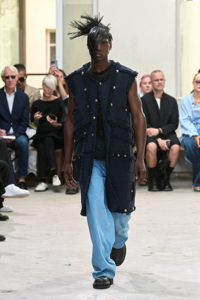 A relaxed navy denim sleeveless vest paired with blue pants featuring button details.