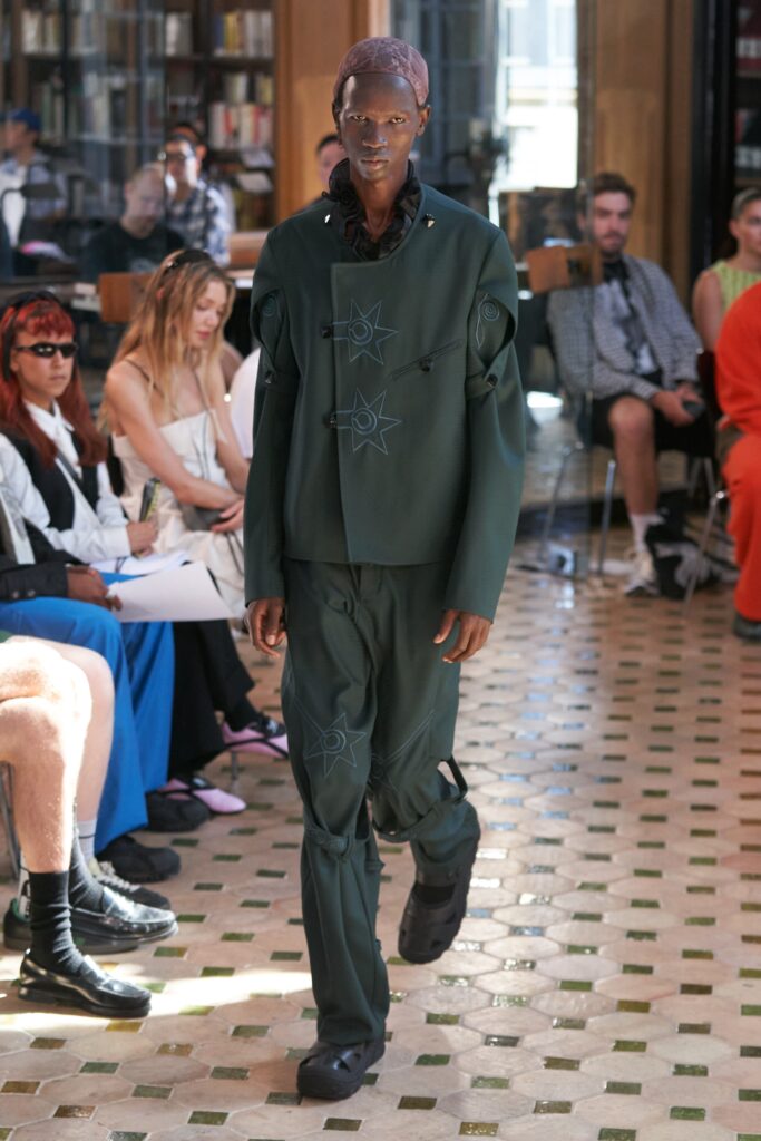 A fitted green neoprene jacket with long sleeves and asymmetric design paired with matching pants.