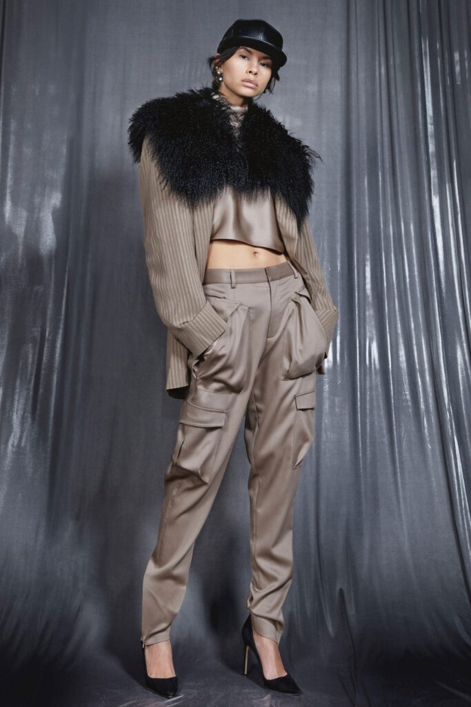 A relaxed beige silk jacket with a fur collar and layered design, paired with black pants.