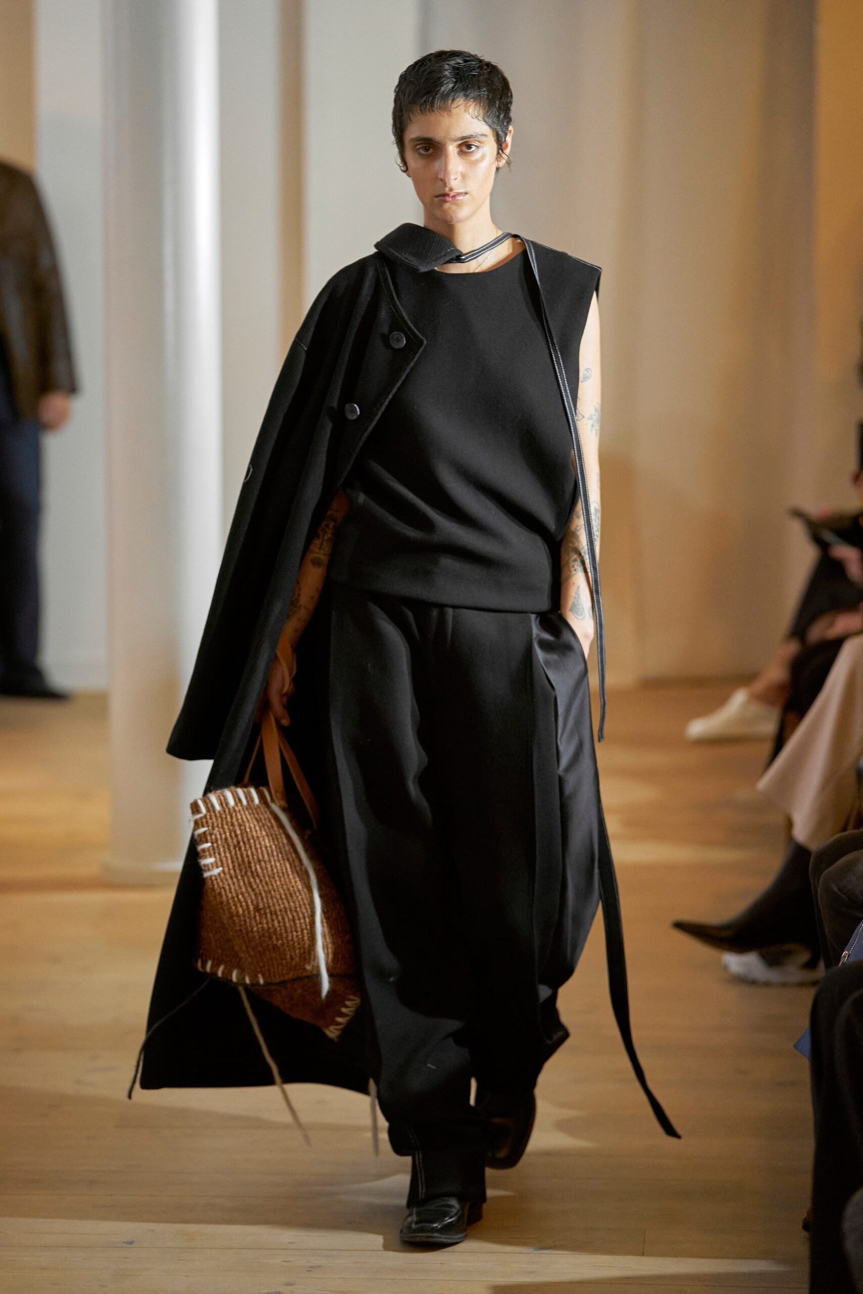 A relaxed black sleeveless top paired with a layered coat for a modern look.