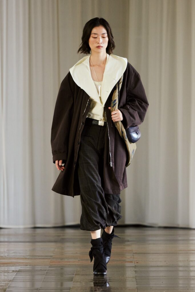 A relaxed brown coat with a collared neckline paired with wide-leg black pants.